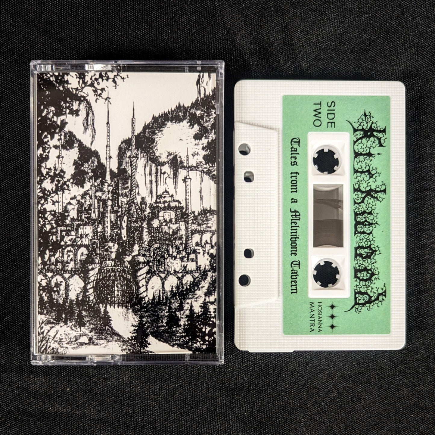 Cassette tape with black and white graphic design on the cover and green label on a black background