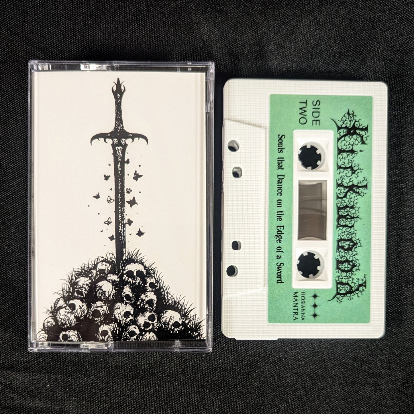 Cassette tape with a sword and skulls design on the cover against a black background
