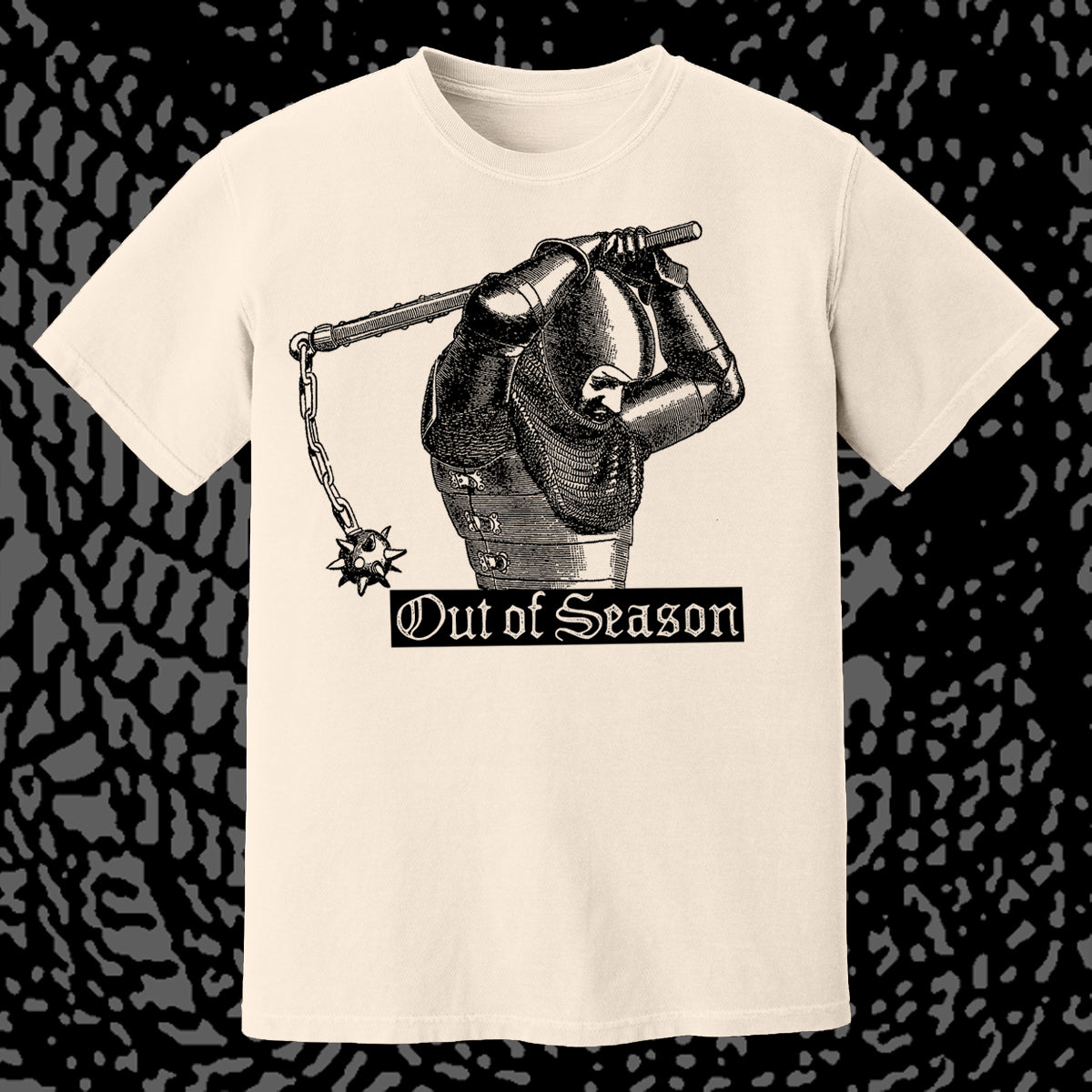 Beige t-shirt with a graphic of a gauntlet holding a sword and 'Out of Season' text on a black patterned background.