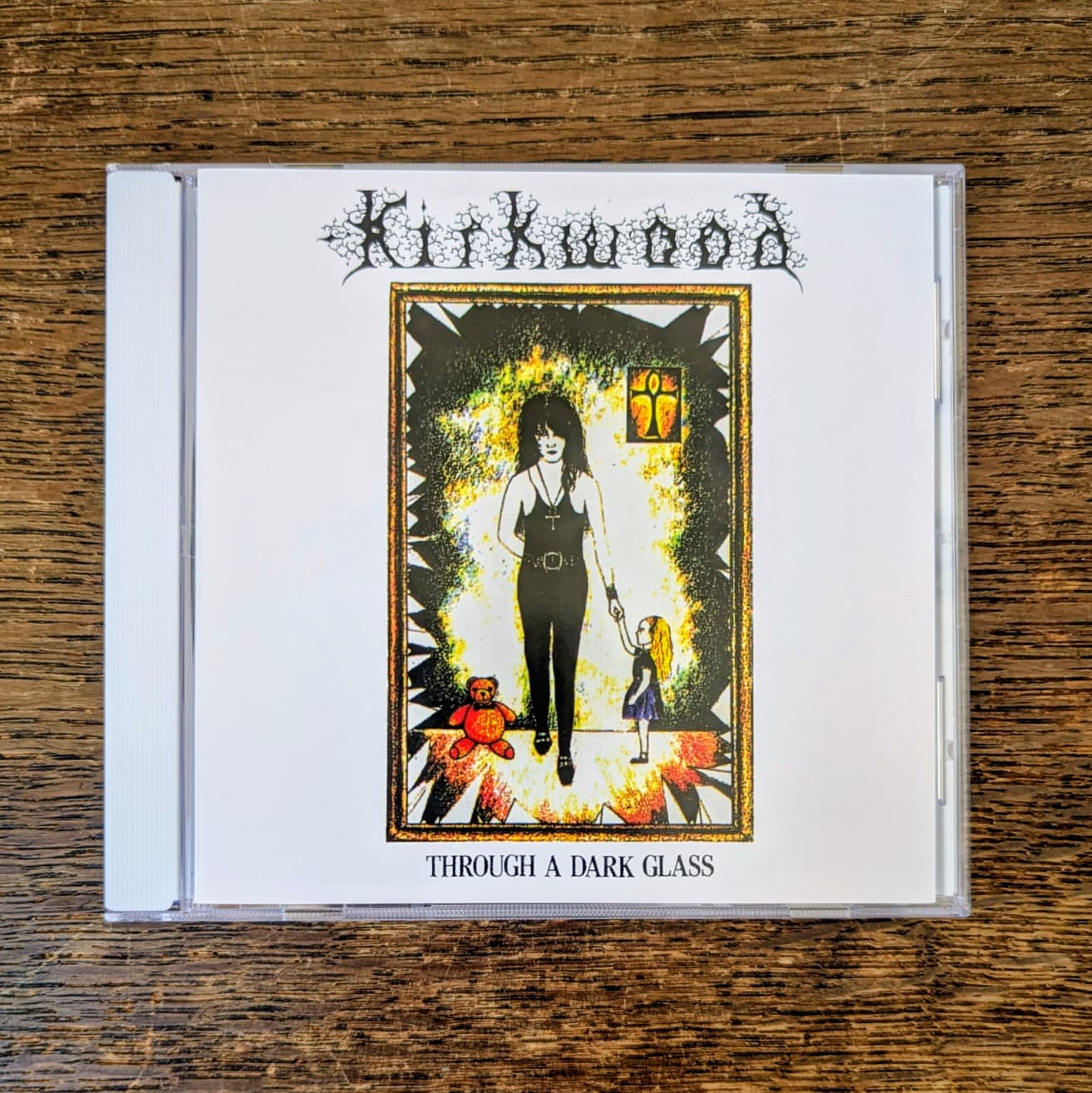 CD cover of 'Kirkwood Through a Dark Glass' on a wooden surface