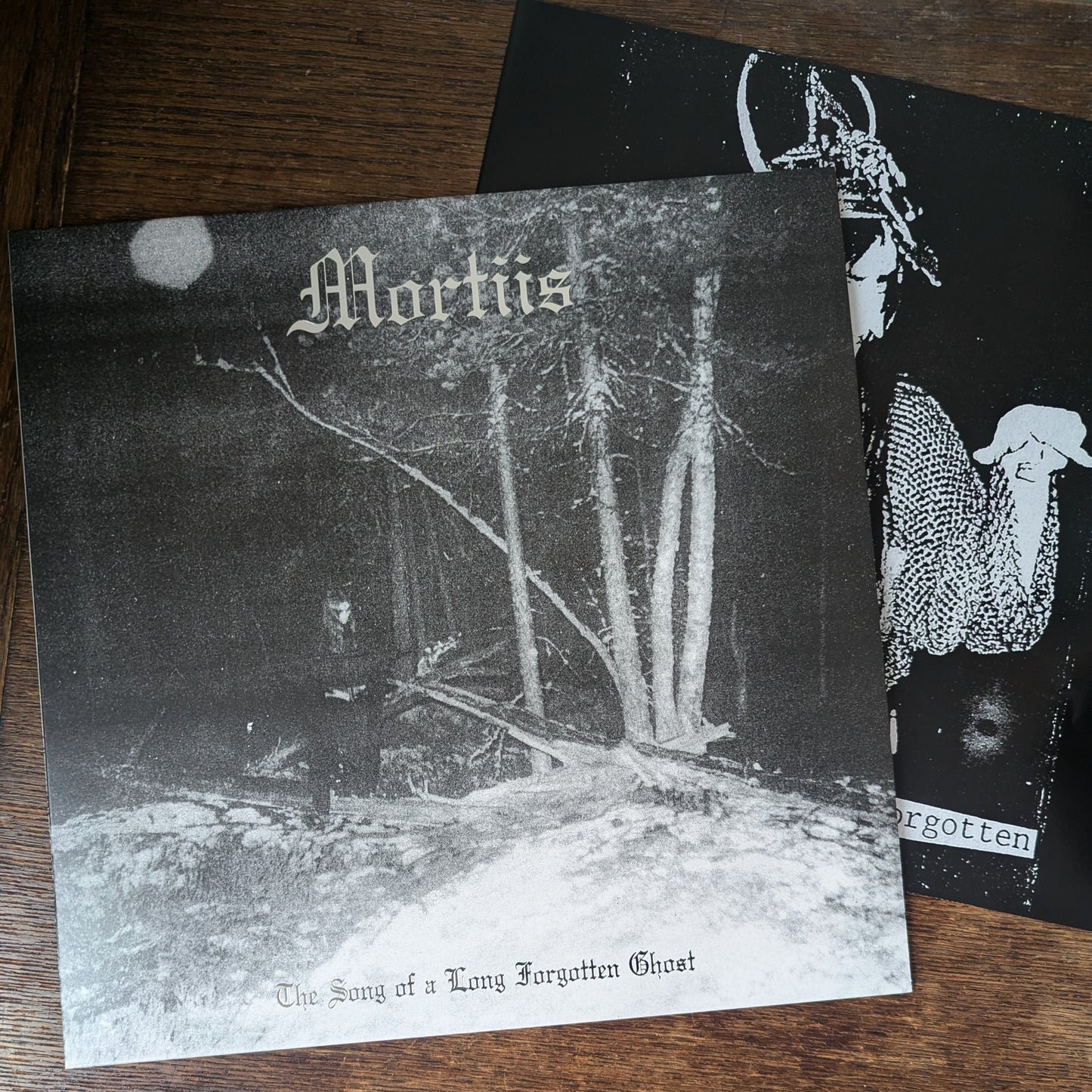 Album cover with text 'Mortiis' and 'Forgotten' on a wooden surface