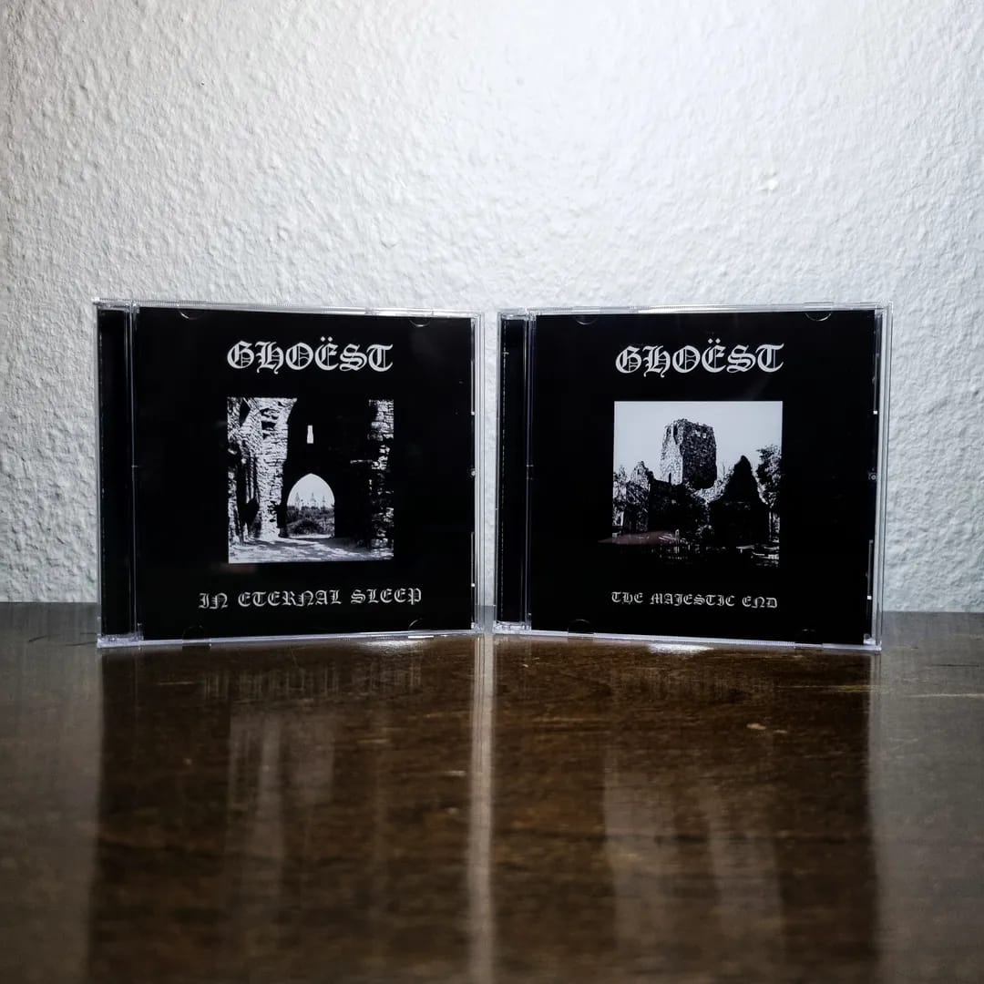 Two black CDs with 'GHOEST' on the cover, featuring black and white images, on a reflective surface.