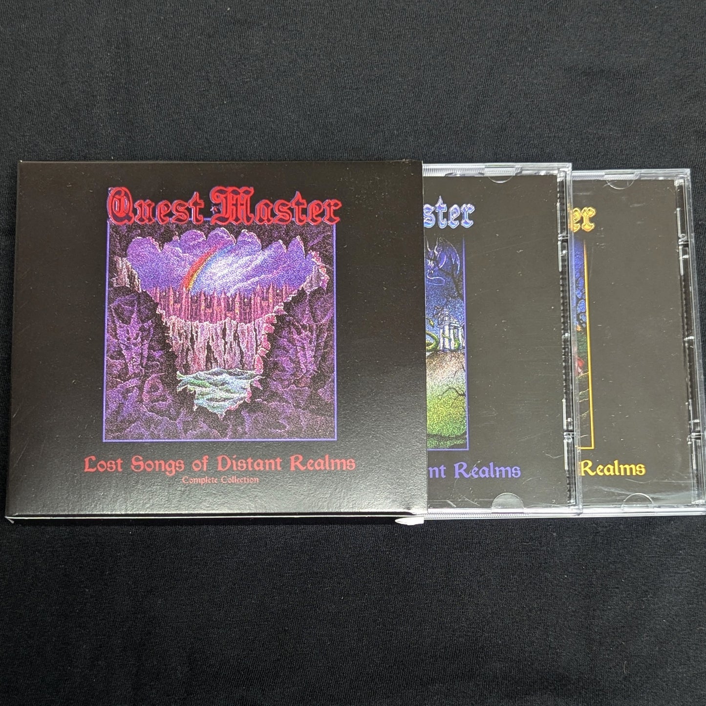 Music album and CD cases with 'Quest Master' cover on a black background