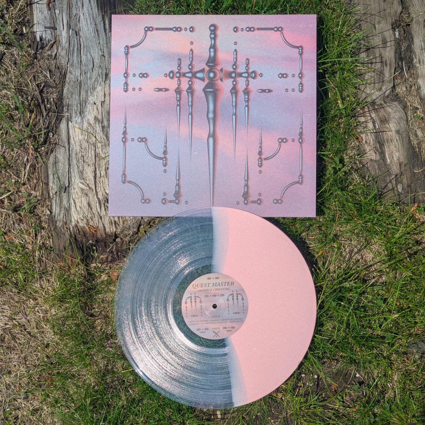 Vinyl record with a pink and clear design on a grassy surface